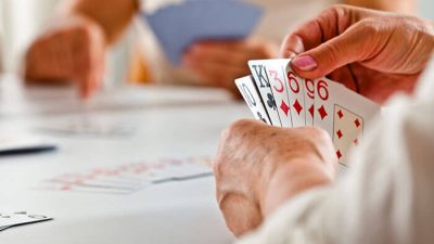 Close-up of players holding cards during a game, demonstrating the dynamics of bluffing and strategy in how to play BS (Bullshit).