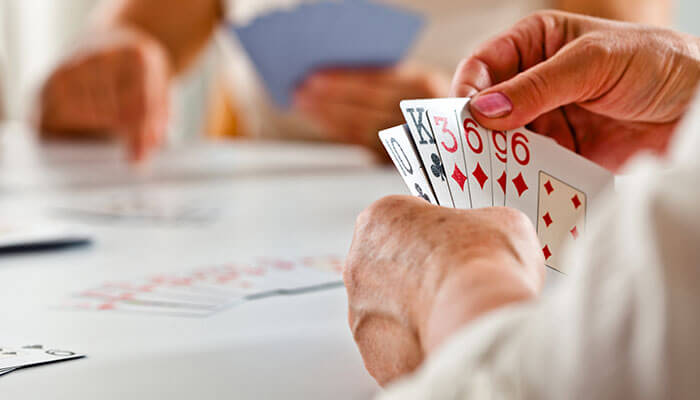 Close-up of players holding cards during a game, demonstrating the dynamics of bluffing and strategy in how to play BS (Bullshit).
