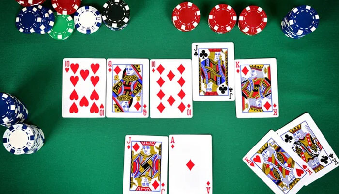 Close-up view of Teen Patti cards and poker chips laid out on a green table, demonstrating an ongoing hand in the game and offering insight into how to play Teen Patti.