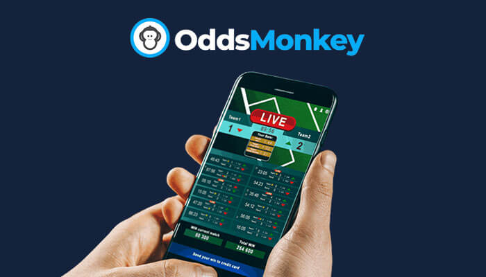 Person holding a smartphone displaying a live sports betting interface with score updates, under the logo 'OddsMonkey' on a dark blue background, highlighting the OddsMonkey betting platform.