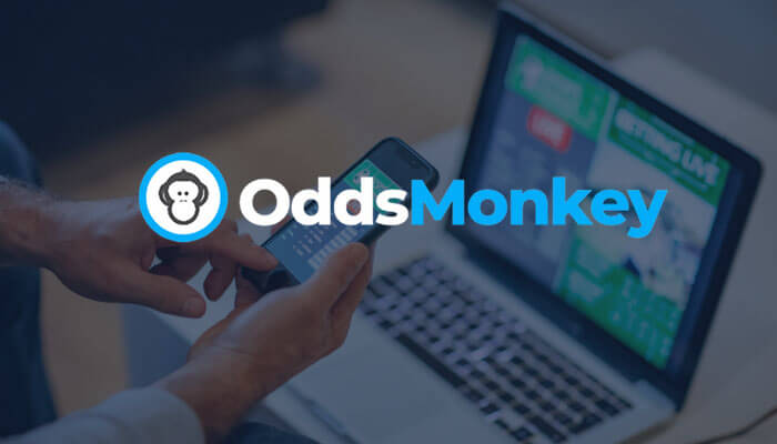 Odds Monkey logo overlaying a person using a smartphone with a laptop displaying live betting odds in the background, representing the Odds Monkey matched betting platform.