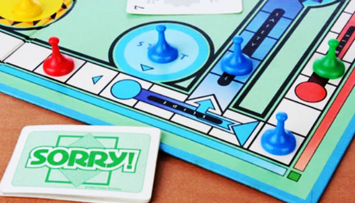 Sorry! board game setup with cards and colorful pawns on the board, illustrating how to play Sorry board game step by step.