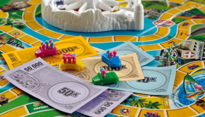 Close-up of The Game of Life board with money, cars, and pegs, illustrating how to play and follow the game of life rules.