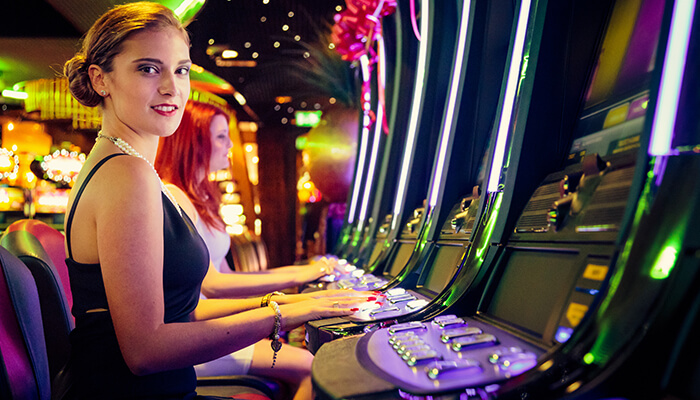 Women enjoying slot machines in a glamorous casino setting, capturing the fun and social spirit of playing at Spree Casino.