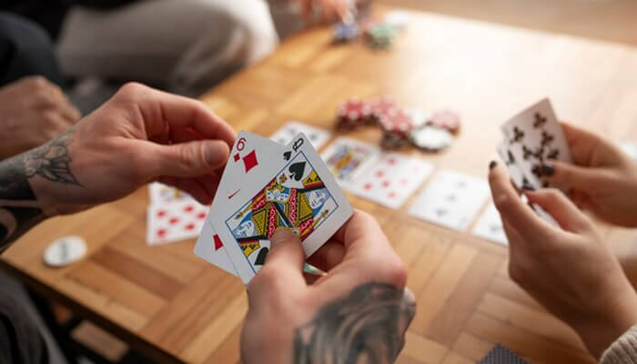 Players sitting around a table exchanging cards in mid-game, demonstrating key gameplay moments from Swoop card game rules and how turns work in this shedding card game.