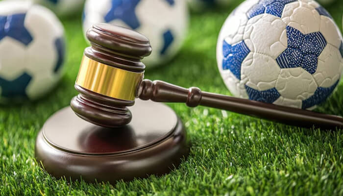 Gavel on green turf with soccer balls symbolizing sports betting laws and regulations related to Sportzino Casino.