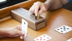 Players in action, using a Cribbage board to tally points, with cards being played, showcasing the gameplay and the process of how to play Cribbage