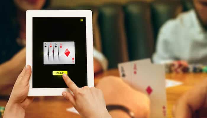 How to Play Bid Whist Card Game Online - Live Casino Magic - Live CasinoMagic Digital card game displayed on a tablet while players sit at a table, demonstrating bid whist rules in an online and offline gaming environment.