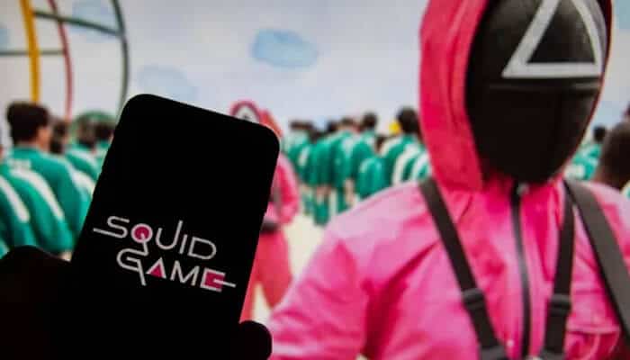What will players do in the Squid Game - Live Casino Magic - Live CasinoMagic Pink-uniformed Squid Game guards oversee players in green tracksuits during a deadly game scene, symbolizing the real-world themes behind the question is squid game based on a true story.