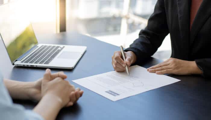 Be Strategic Not Random With Your Job Applications - Live Casino Magic - Live CasinoMagic drovenio it career tips usa concept showing a strategic job application process, candidate reviewing and signing documents during an interview, emphasizing targeted applications, resume optimization, and networking for IT careers in the USA