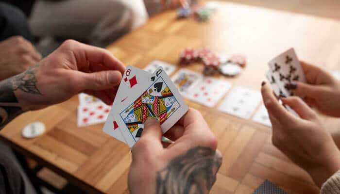 How do you play the card game golf - Live Casino Magic - Live CasinoMagic Hands holding playing cards with poker chips on the table, illustrating the gameplay for Golf card game rules