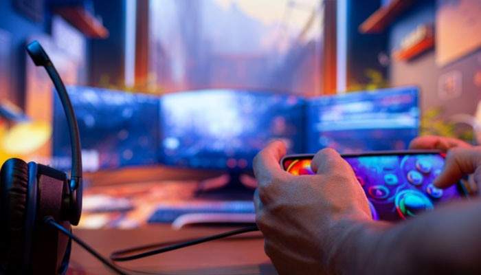 Use Gaming Apps and Notification Tools - Live Casino Magic - Live CasinoMagic How to Keep Up With Gaming News TheHakeTech image showing a gamer using a smartphone beside a headset and multi-monitor gaming setup to follow game updates, notifications, releases, patch notes, and esports news.